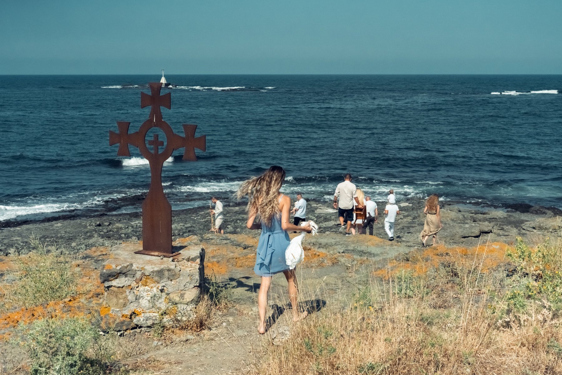 Крайбрежният кръст и семейството, събрано край водата преди ритуала.